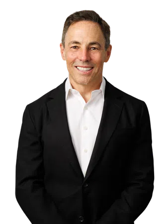 Middle-aged man smiling wearing a black suit jacket and white dress shirt on white background.