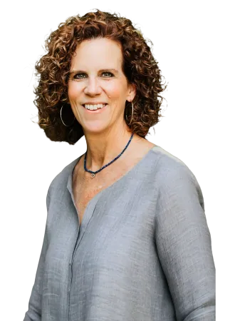 Smiling woman with curly hair wearing a light gray blouse and hoop earrings against a transparent background