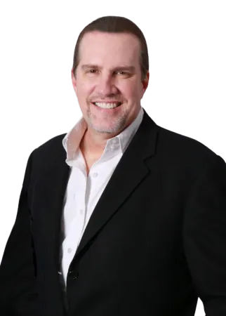 Smiling man in black suit jacket and white shirt with a short beard and slicked-back hair.