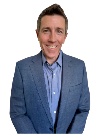 Smiling man in a blue blazer and shirt posing against a transparent background.