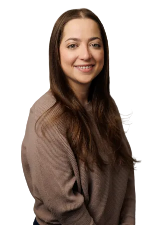 Smiling woman with long brown hair wearing a textured taupe sweater against a black background