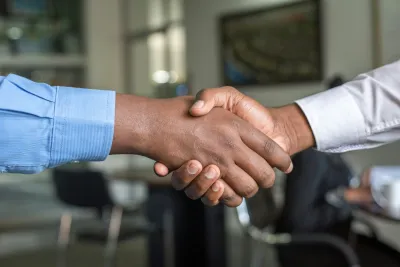Close-up of two people shaking hands in a professional office setting symbolizing agreement and partnership.