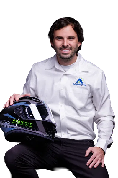 Man in Andretti shirt holding a black Andretti racing helmet, smiling on a black background.