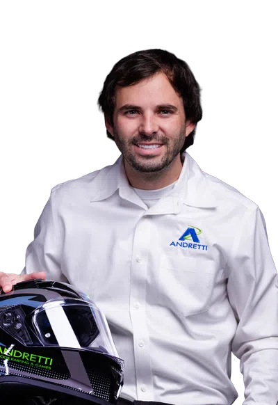 Man in Andretti shirt holding a black Andretti racing helmet, smiling on a black background.