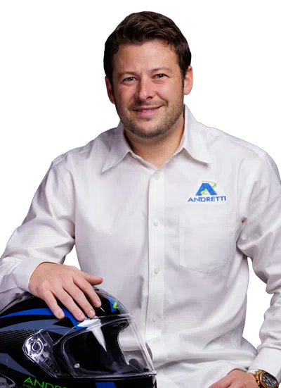 Man in white Andretti shirt holding a black and blue racing helmet with Andretti branding