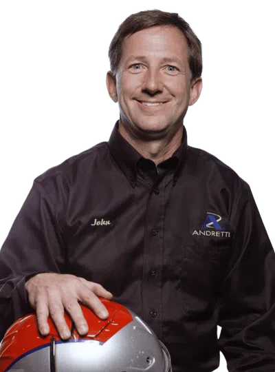 Man in Andretti shirt holding a racing helmet with Honda logo and American flag design, smiling
