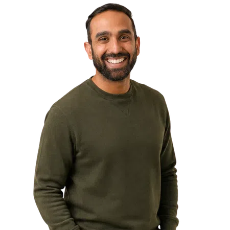 Smiling man with beard wearing an olive green sweater standing against a transparent background.
