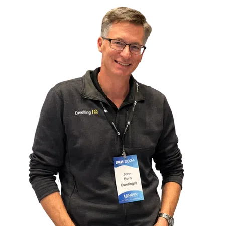 Smiling man wearing glasses and Dwelling IQ jacket with IMH 2024 conference badge around his neck.