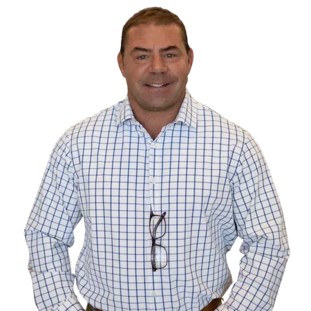 Smiling man wearing a white shirt with blue grid pattern and glasses hanging from the collar.
