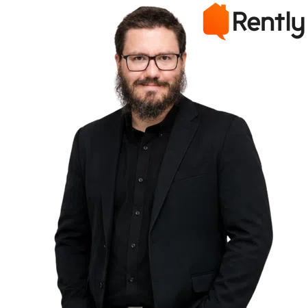 Man with glasses and beard wearing black suit and shirt, smiling confidently on dark background with Rently logo