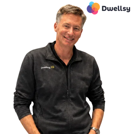 Smiling man wearing a black Dwelling IQ zip-up jacket with Dwelly logo in the top right corner