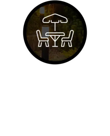 Icon of outdoor patio table with umbrella and chairs illuminated by outdoor lighting at night.
