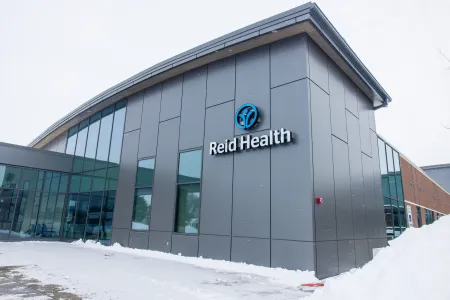 Reid Health medical facility building exterior with gray panels and snow on the ground in winter.