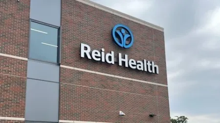 Reid Health medical building with brick facade, logo, and landscaped walkway on a cloudy day.