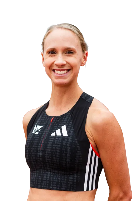 Smiling female athlete wearing a black Adidas sports crop top with white stripes and logo.