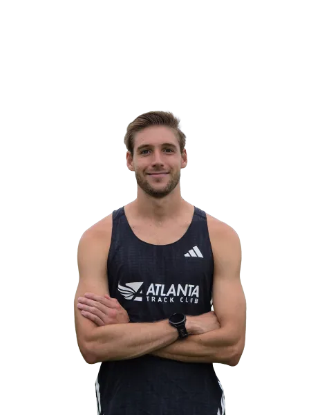 Smiling male athlete in black Atlanta Track Club tank top with arms crossed and smartwatch on wrist.