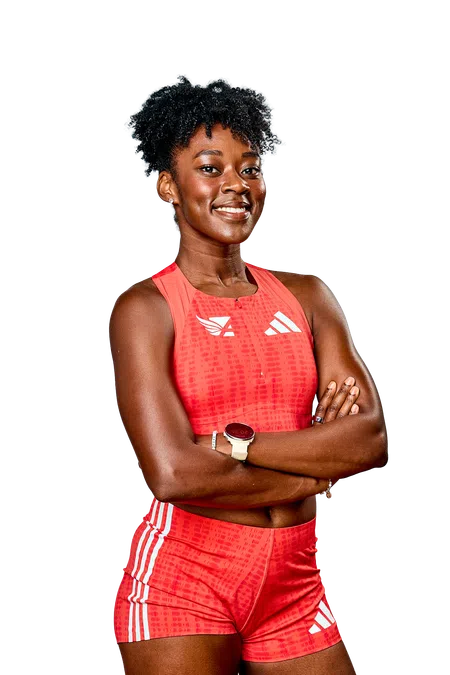 Confident female athlete in red sportswear with arms crossed smiling against black background