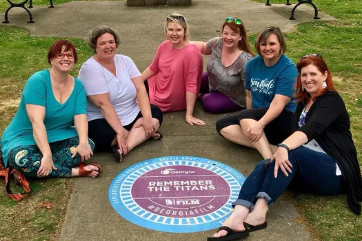 Berry alumnae sit on ground at 2018 reunion at Remember the Titans selfie spot