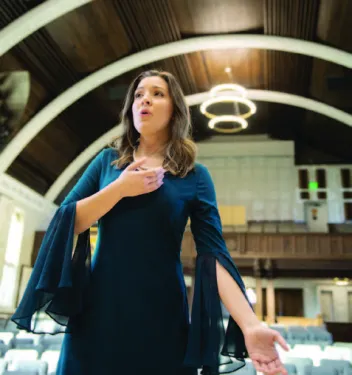 Berry alumna wears a teal dress and sings in the empty Ford auditorium