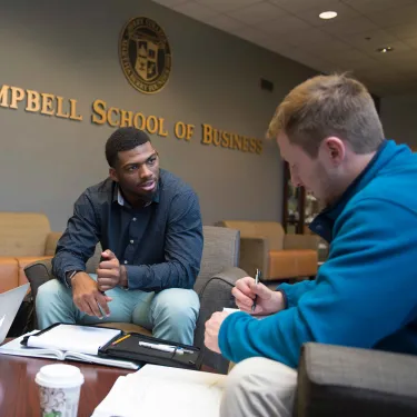 a couple of men sitting at a table looking at a paper