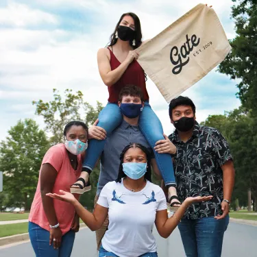 Berry students pose wearing masks holding a sign that says "GATE est. 2003"