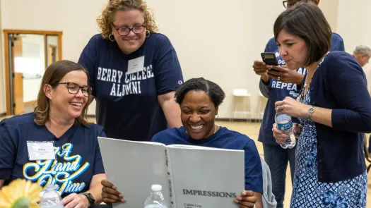 a group of people standing around a table with a laptop