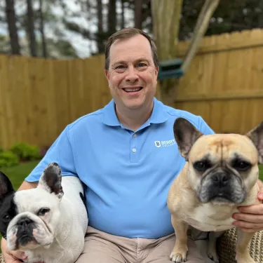Berry alum sitting outside with two dogs