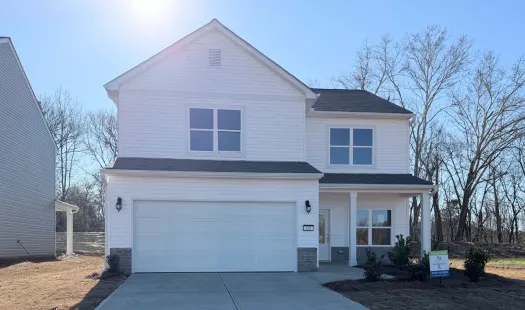 New two-story white house with attached garage and concrete driveway under a clear blue sky.