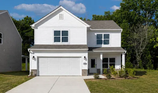 Modern two-story white house with large driveway, attached garage, and green lawn under blue sky.