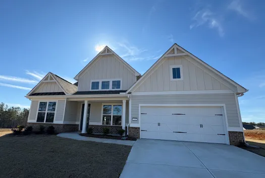 Modern single-story white house with a large driveway, garage, and a well-kept lawn under a clear blue sky.