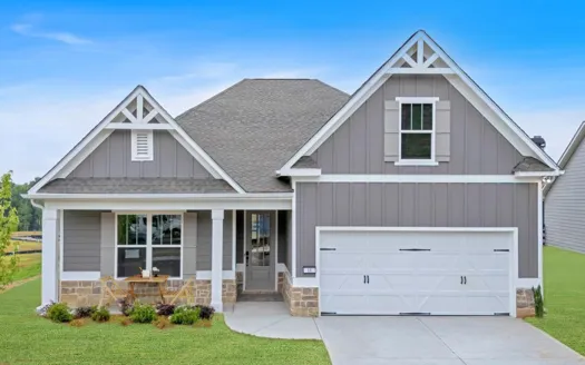 Modern gray house with stone accents, front porch, white garage door, and well-kept lawn under a clear blue sky