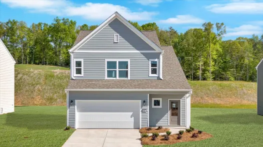 Modern two-story gray house with garage, front yard landscaping, and green trees in background under blue sky