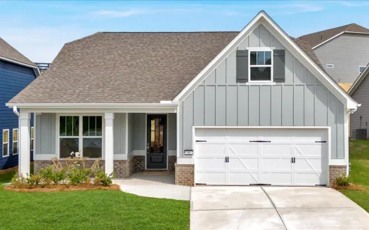 Modern single-story house with gray siding, white garage door, front porch, and green lawn under blue sky