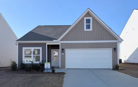 Single-story modern townhouse with a two-car garage and a clean concrete driveway under clear blue sky.