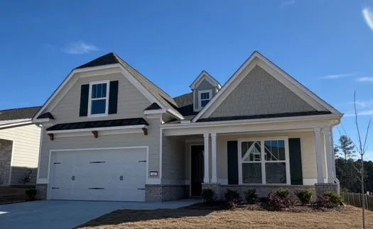 Modern suburban house with a two-car garage, manicured lawn, and clear blue sky on a sunny day.