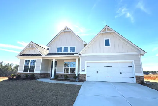 New modern single-family home with white siding, brick accents, front porch, and a two-car garage under a clear blue sky