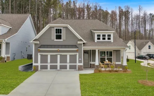 Modern gray house with a welcoming porch and manicured lawn in a suburban neighborhood.