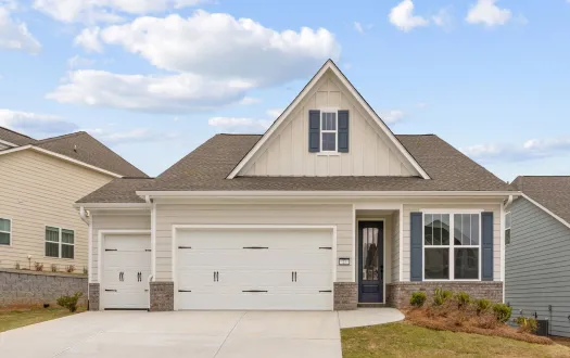 Single-story modern house with a two-car garage, light beige siding, gray shutters, and a spacious concrete driveway under blue sky.
