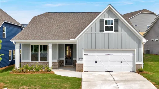 Modern gray house with white garage door, brick accents, and front porch with green lawn and driveway