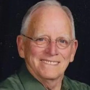 a man wearing glasses and smiling at the camera
