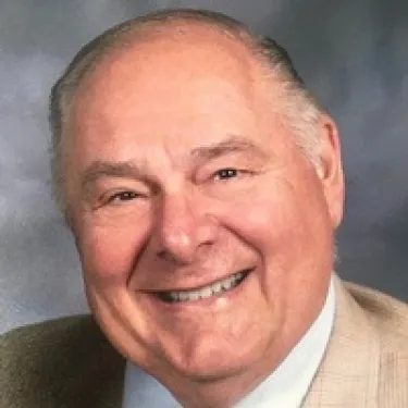 a man wearing a suit and tie smiling at the camera