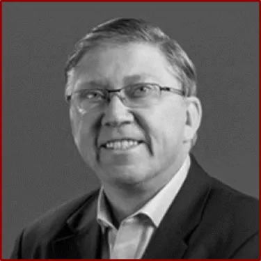 a man wearing a suit and tie smiling at the camera