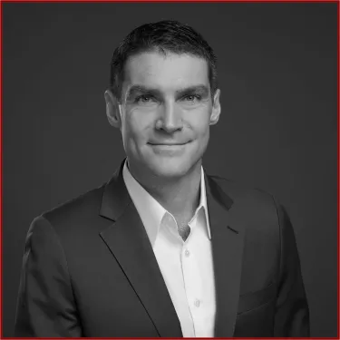 a man wearing a suit and tie smiling at the camera