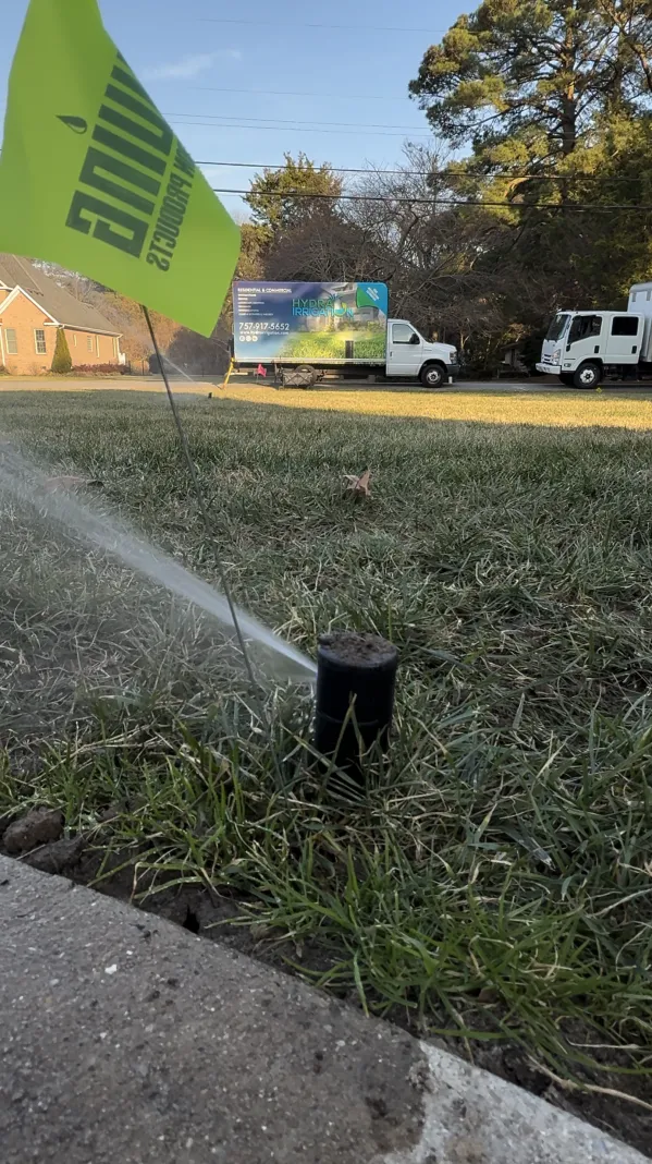 Sprinkler head spraying water on grass with a service truck in the background.