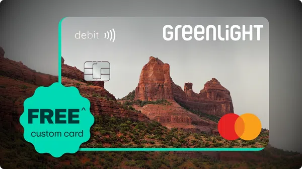 Greenlight debit card featuring a scenic red rock mountain background with free custom card offer badge.