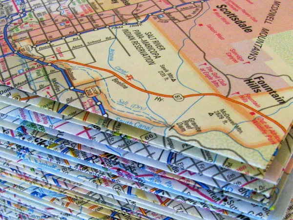 Stack of folded road maps showing routes, cities, and landmarks including Scottsdale and Fountain Hills, Arizona.