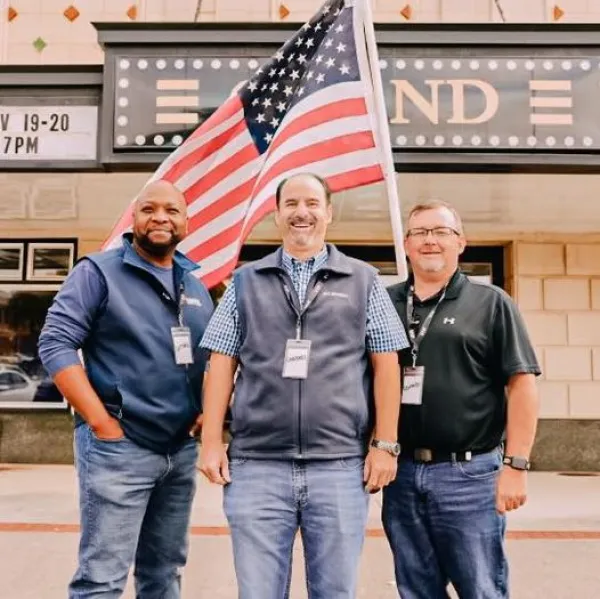 a group of men posing for a photo in front of a building