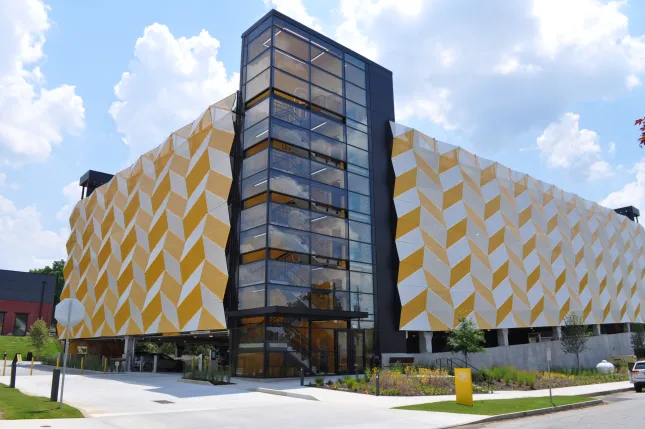 Modern multi-story parking garage with yellow and white geometric facade under a blue sky