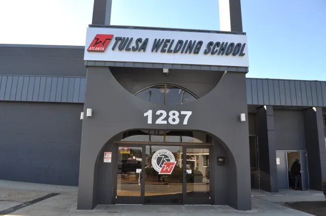 Front entrance of Tulsa Welding School building with signage and address number 1287 under clear blue sky.