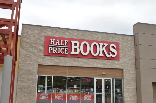 Half Price Books storefront with large red and white sign above entrance and promotional window displays
